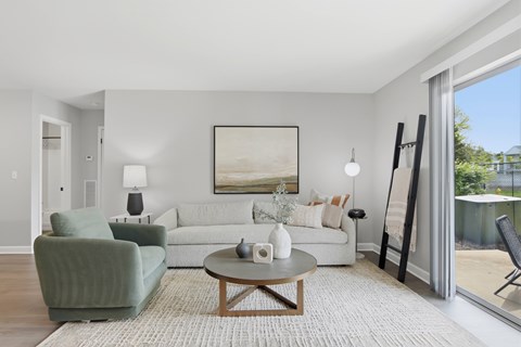A living room with a green chair, a white couch, and a painting on the wall.