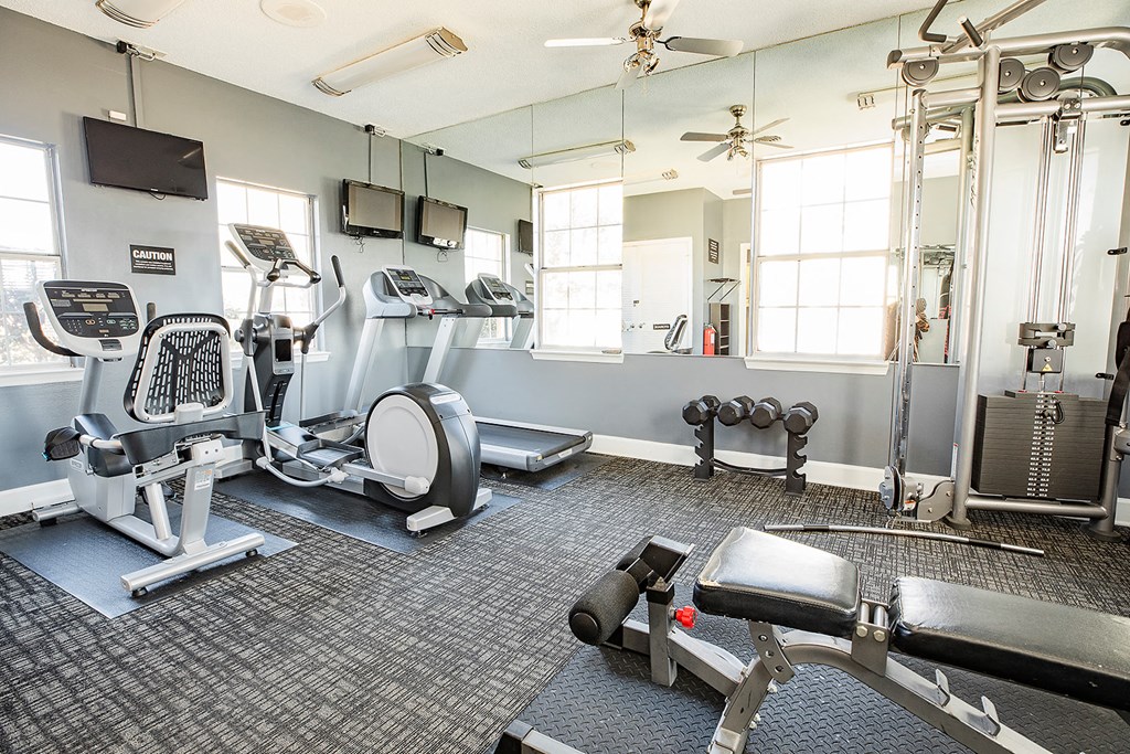 a gym with cardio equipment and windows