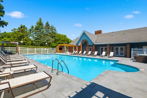 A pool with sun loungers and a building in the background.