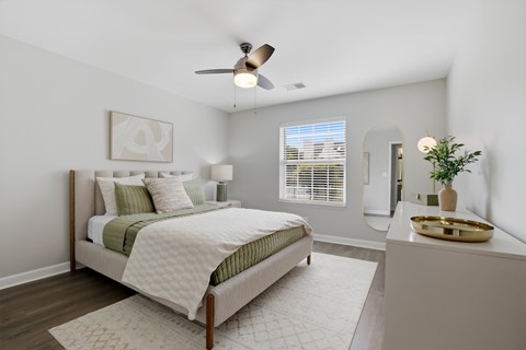 A bedroom with a bed, a fan, and a nightstand.