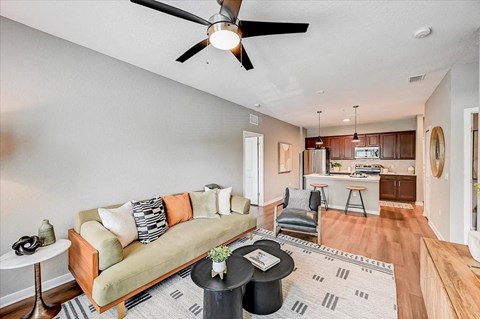 A living room with a green couch and a ceiling fan.