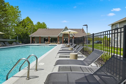 A pool with a black fence and a house in the background.