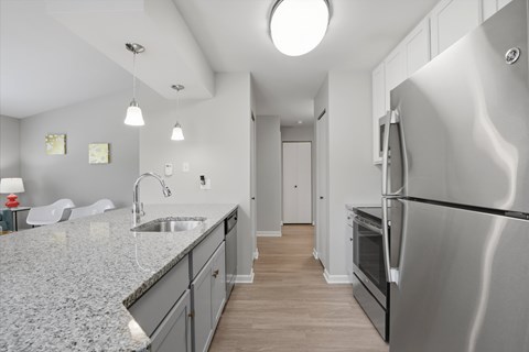A modern kitchen with a stainless steel refrigerator and a marble countertop.
