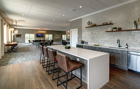 a kitchen with a counter and chairs in front of a bar