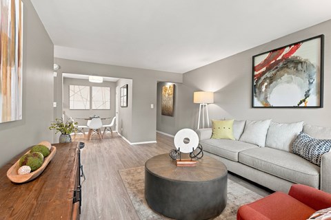 A living room with a grey couch, a coffee table, and a large painting on the wall.