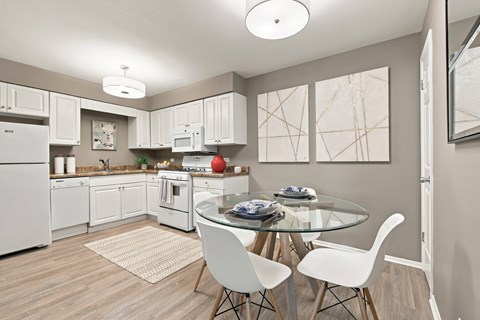 A modern kitchen with a glass table and white chairs.