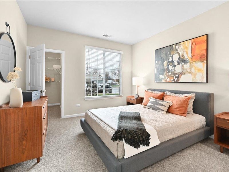 furnished bedroom with wall art, a walk-in closet, and a large window in a Farmington Lakes home