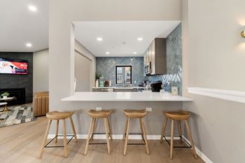 A kitchen with a bar area and three stools.