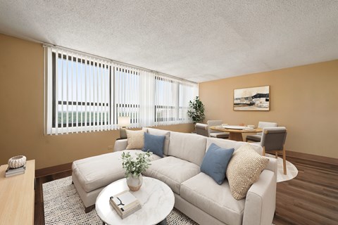 A living room with a white couch, a coffee table, and a dining table with chairs.