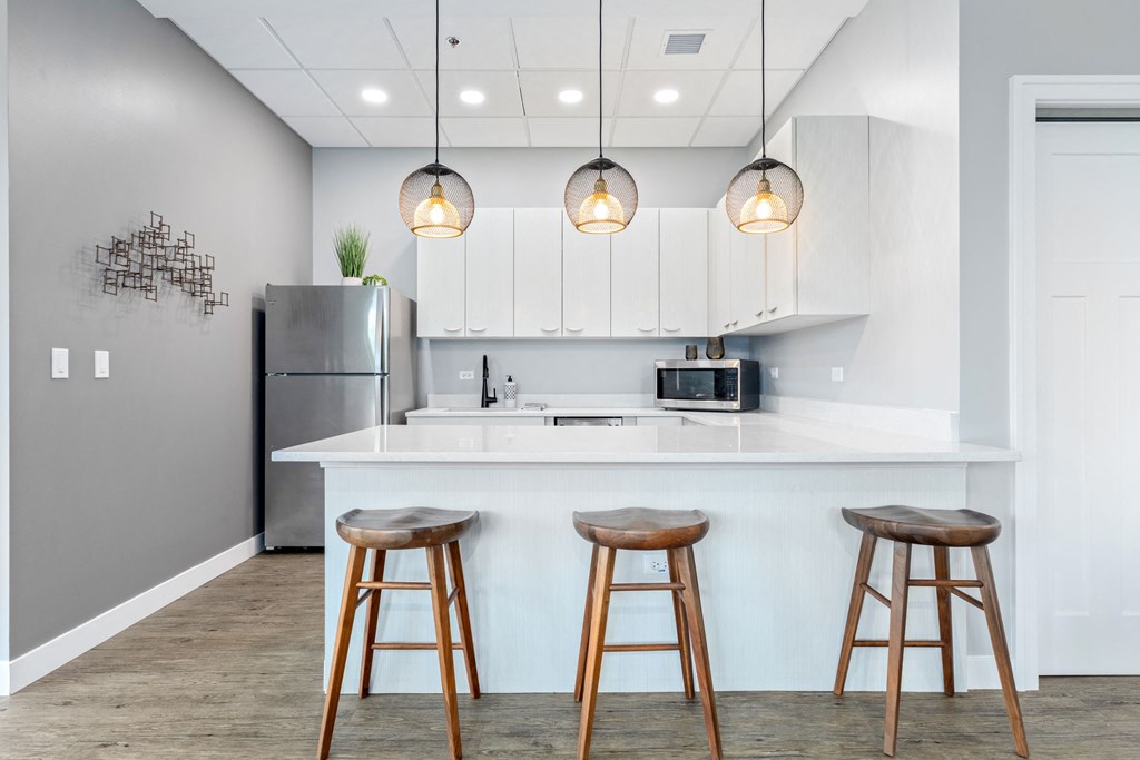 a kitchen with white cabinetry and a large white island with three wooden stools