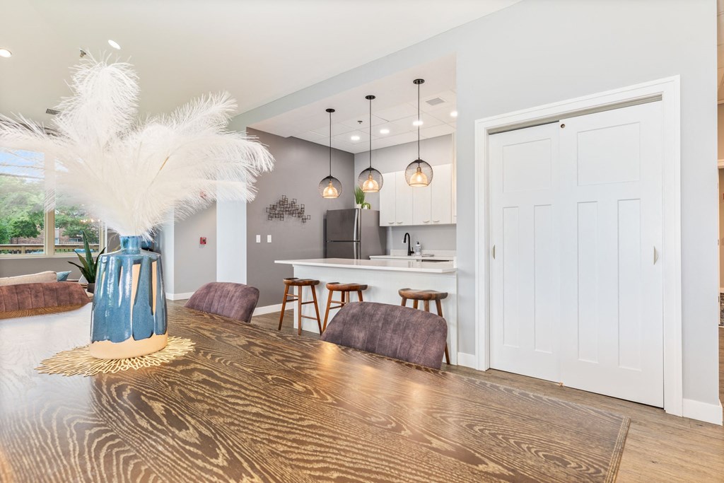 a dining area with a wooden table and chairs and a kitchen in the background