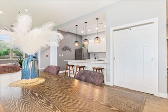 a dining area with a wooden table and chairs and a kitchen in the background - Photo Gallery