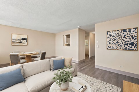 A living room with a white couch and a painting on the wall.