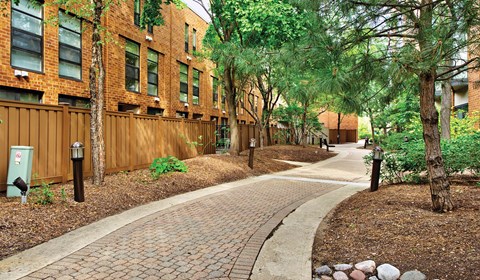 A brick pathway leads through a landscaped area between two buildings.