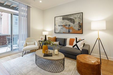 A living room with a grey couch, a white chair, a coffee table, and a painting on the wall.