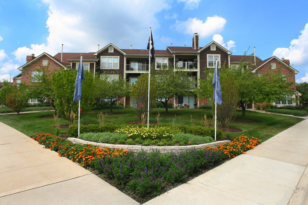 a garden with flags in front of an apartment building
