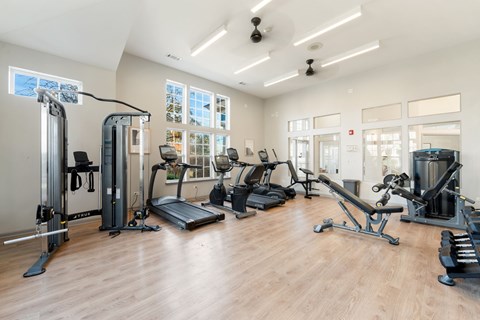 A gym with a variety of equipment including treadmills, weights, and exercise machines.