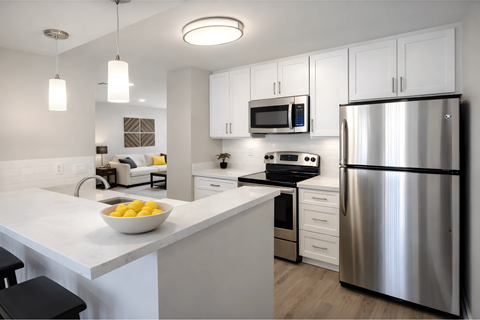 A modern kitchen with a stainless steel refrigerator and a bowl of lemons on the counter.