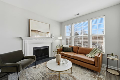 A living room with a fireplace, a couch, a chair, a coffee table, and a painting on the wall.