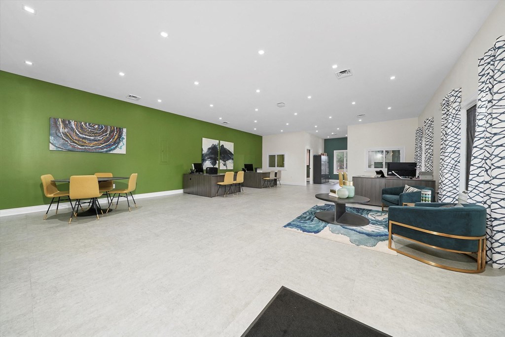 a large lobby with chairs and tables and a green wall