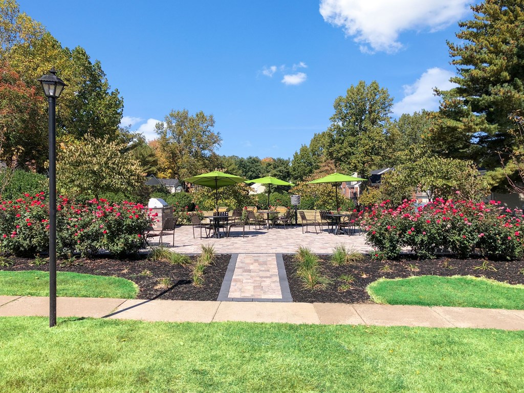 a patio with umbrellas and tables in a garden
