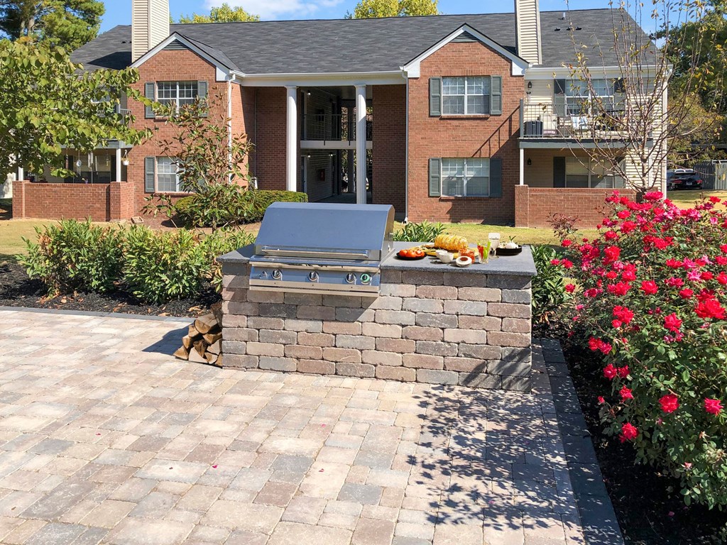 a brick patio with a grill in front of a house
