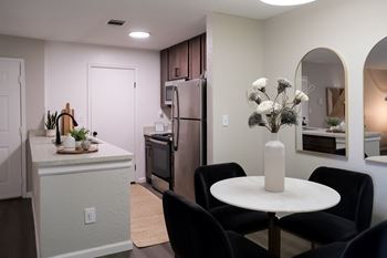 a dining area with a small white table and four black chairs