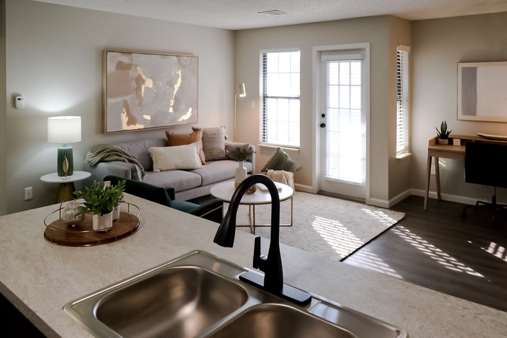 a kitchen with a sink and a doorway into a living room