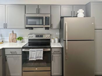 a kitchen with gray cabinets and stainless steel appliances
