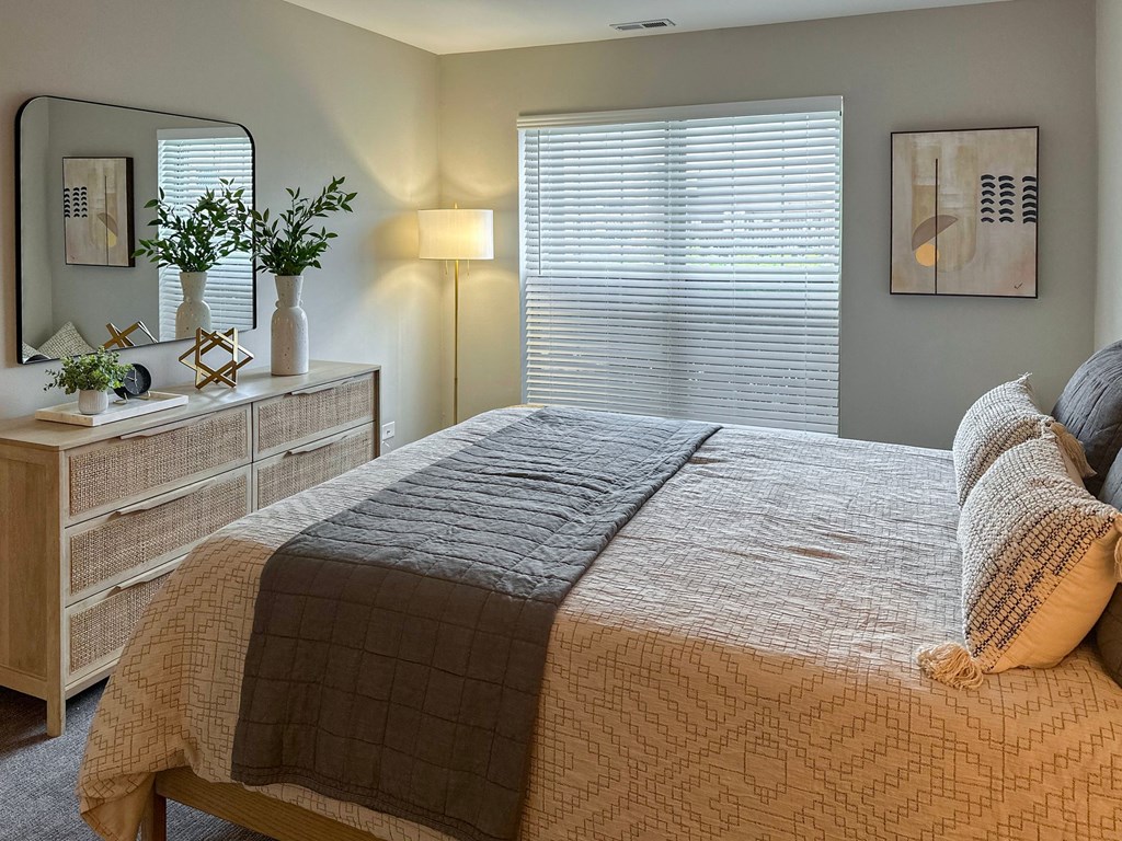 a bedroom with a large bed and a dresser with a mirror