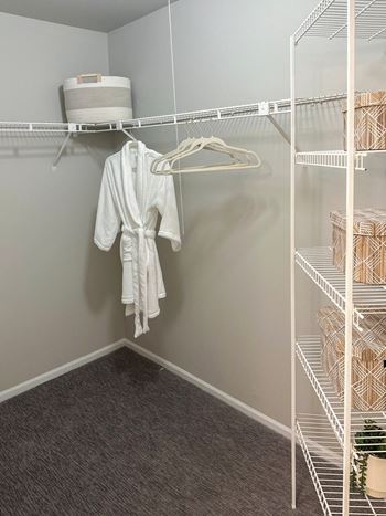 spacious closet with built-in shelving and a robe hanging from the rack