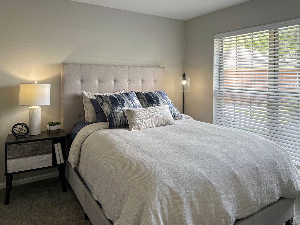 furnished apartment bedroom with a bed and nightstand