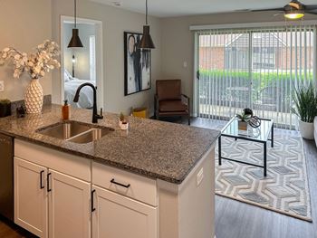 kitchen opening up to a furnished living room of a Green Trails apartment