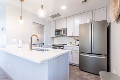 a white kitchen with stainless steel appliances and a white counter top