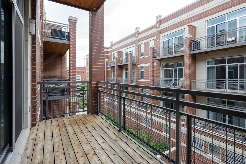 A balcony with a black railing and a wooden floor.