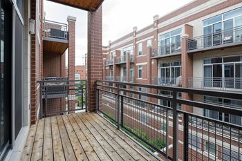 A balcony with a black railing and a wooden floor.