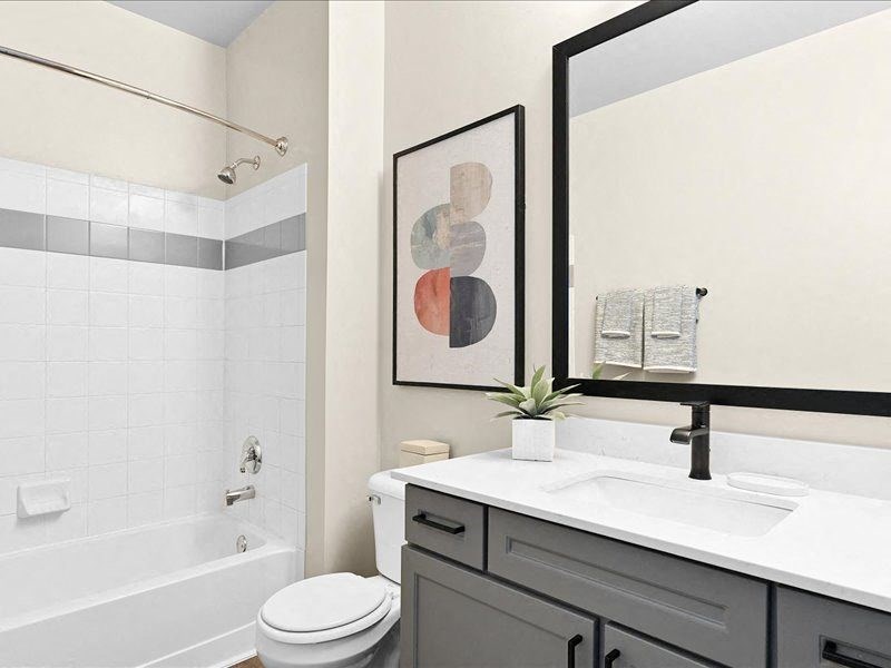 bathroom with modern gray cabinets and a tub in a Farmington Lakes home