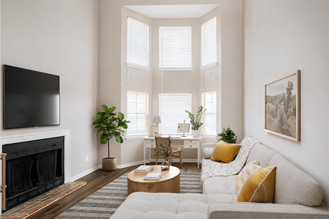 A living room with a grey couch, a fireplace, and a painting on the wall.