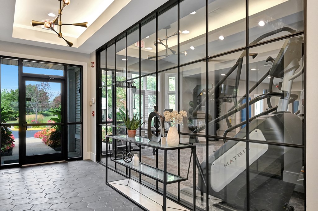 hallway with a large floor to ceiling window looking in to a community fitness center