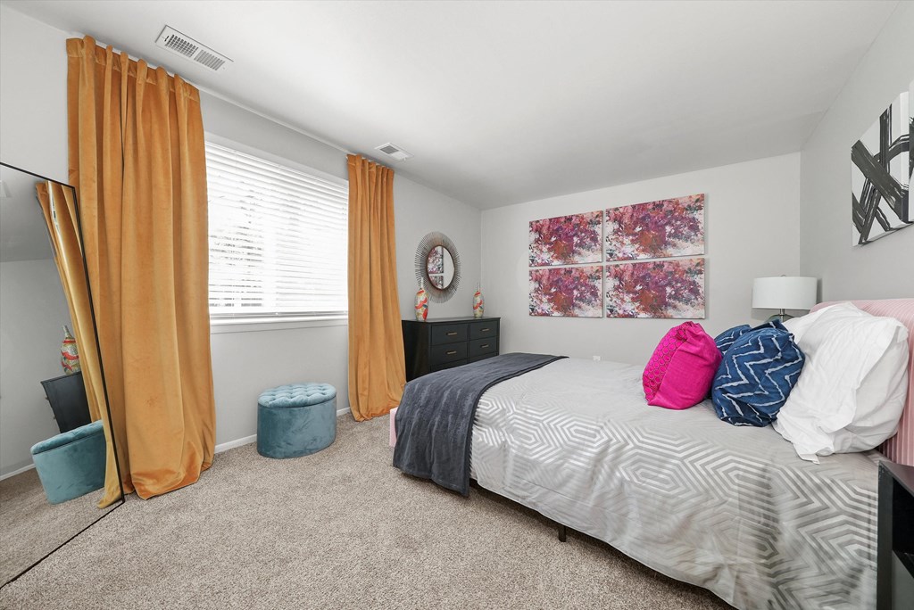 a bedroom with a bed and a window with orange curtains