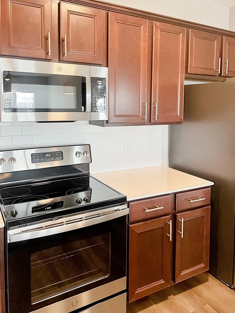 A kitchen with brown cabinets and a stainless steel oven.