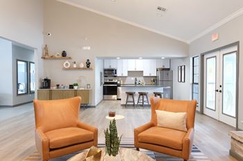 orange chairs and a resident kitchen in The Addison at Southfield clubroom