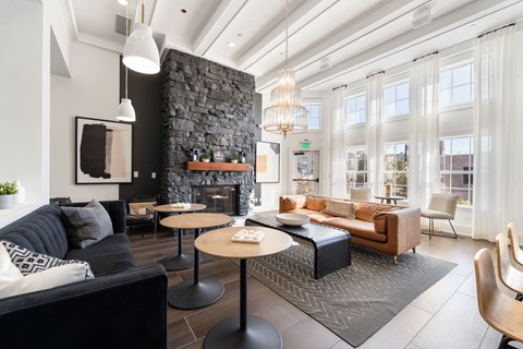 A modern living room with a black couch and a stone fireplace.