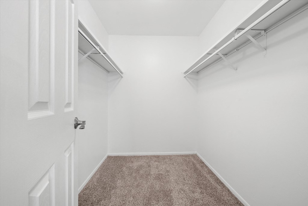 an empty room with white walls and carpet and a door to a closet