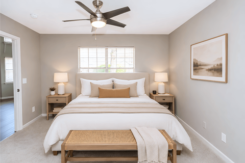 A bedroom with a large bed and a ceiling fan.
