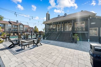 A patio with a table and chairs is in front of a house.