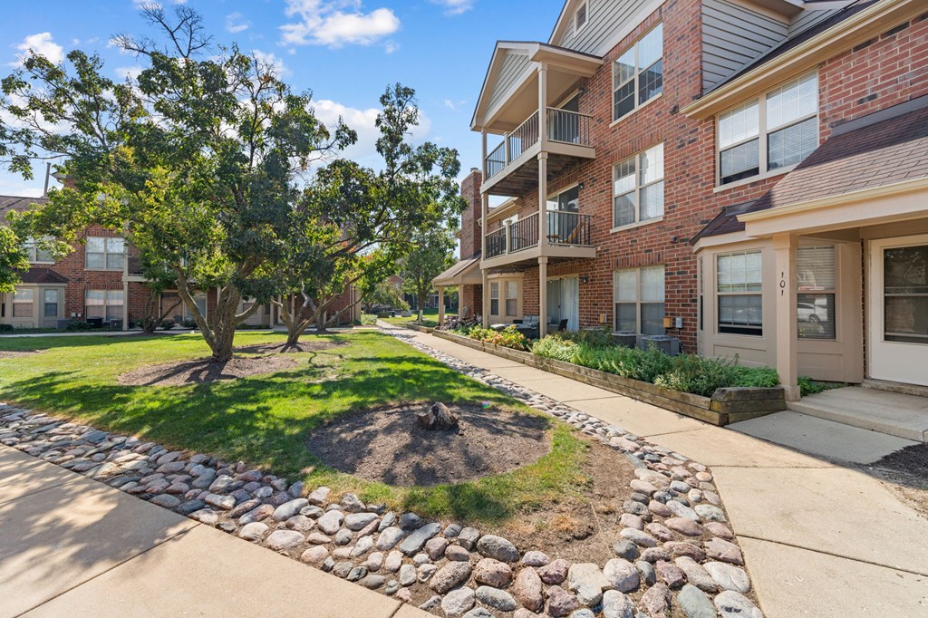 A tree in a grassy area in front of apartment buildings.