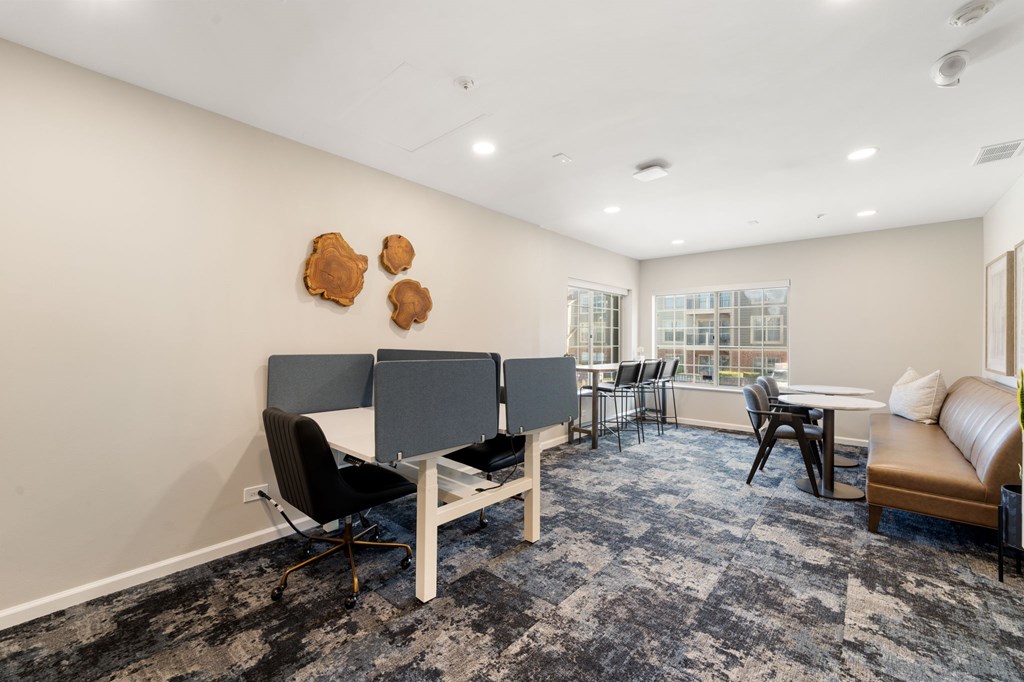 A room with a grey carpet and a white table with chairs.