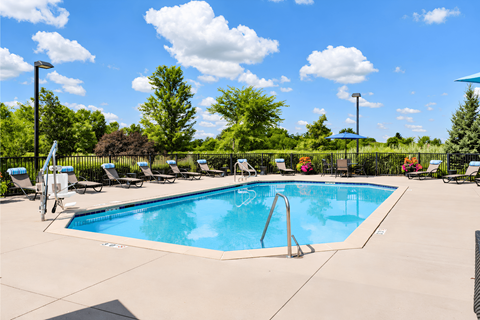 A large swimming pool surrounded by chairs and trees.