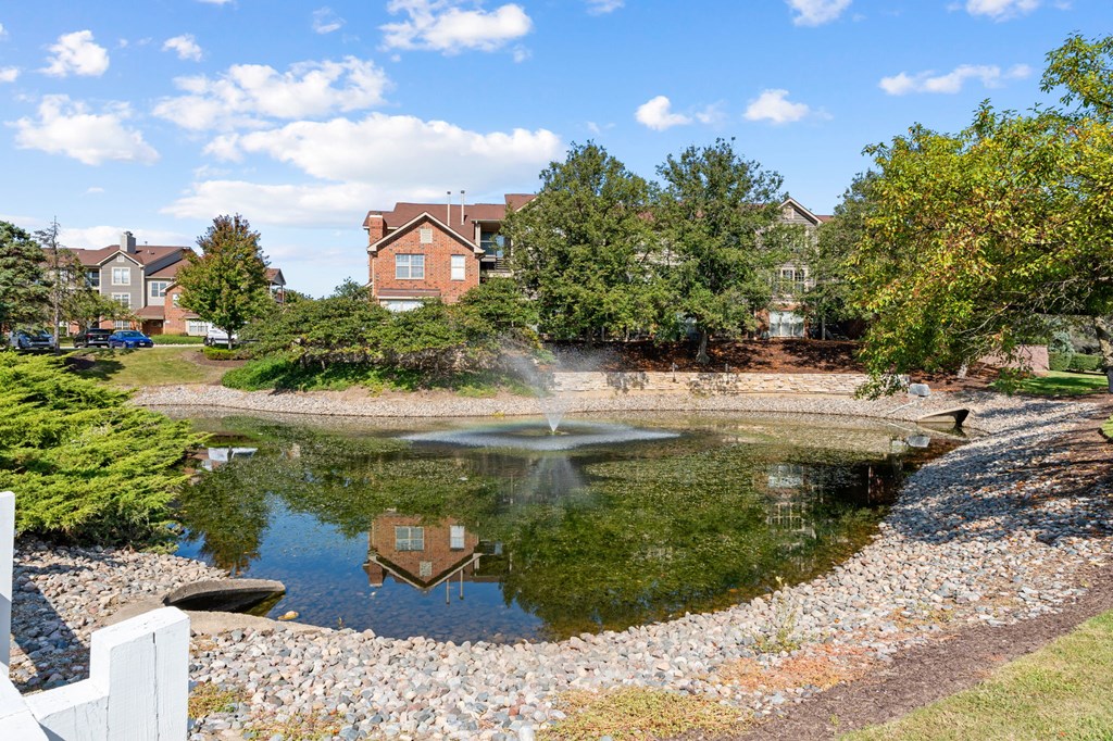 A pond with a fountain in the middle of a residential area.